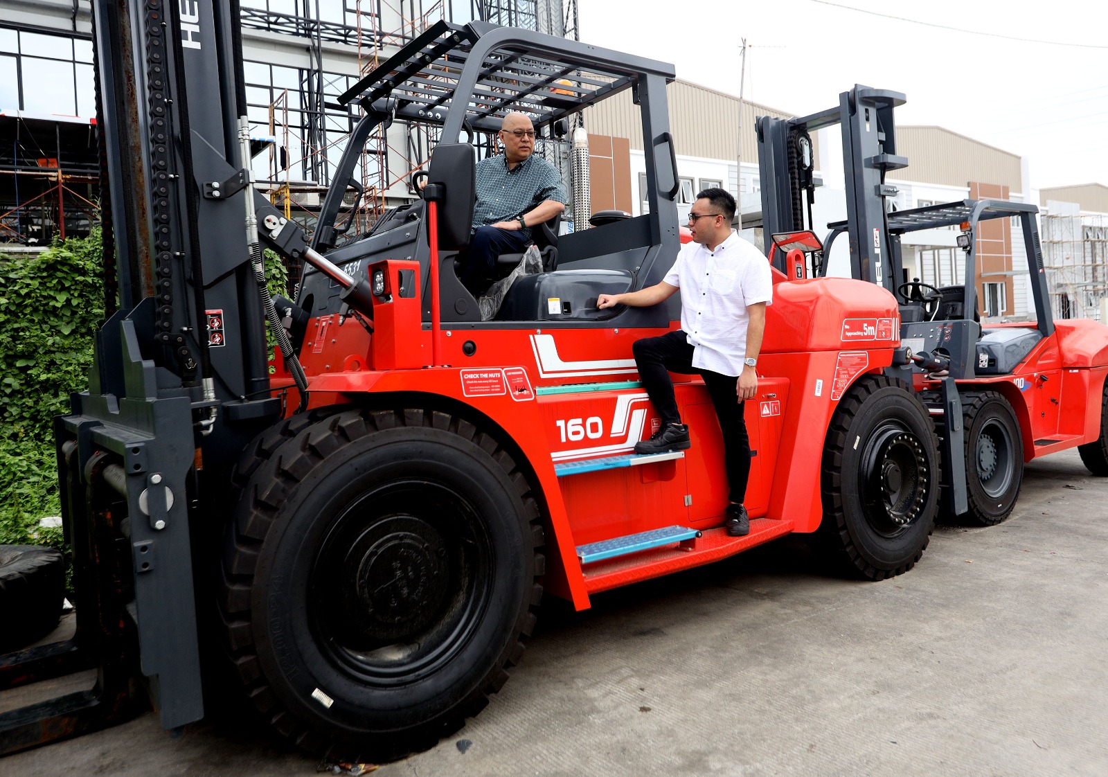 Kiri-Kanan: Hadi Suhermin Direktur Utama dan Winston Suhermin Direktur PT Sarana Mitra Luas Tbk (SMIL) saat berada di atas Forklift dengan kekuatan mengangkat beban hingga 30 ton. DOK/SMIL Sarana Mitra Luas (SMIL) Optimis Permintaan Forklift Melonjak di 2025
