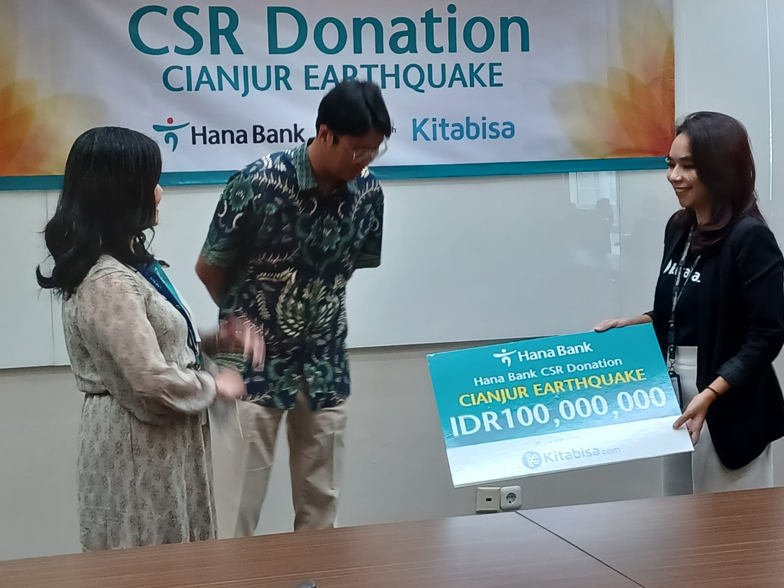 Chief of Human Capital & Operations Bank Hana, Sumia (kiri) dan Strategy Planning Head, Bank Hana, Lim Seong Dong (tengah) menyerahkan donasi secara simbolis kepada Head of Brand Partnership Kitabisa.com, Marisa Thara Wardani (kanan). dok. ist. Bank Hana Serahkan Bantuan Kemanusiaan untuk Korban Gempa Cianjur