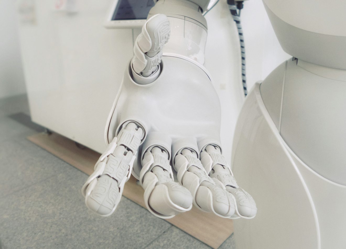 The open white articulated hand of a service robot extended palm upward in a bright interior